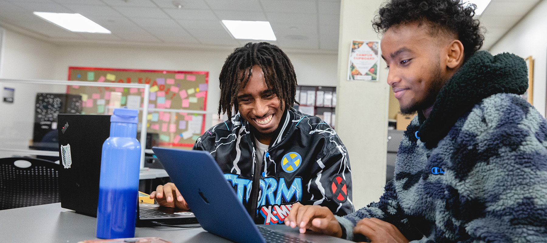 Two students work on a laptop.
