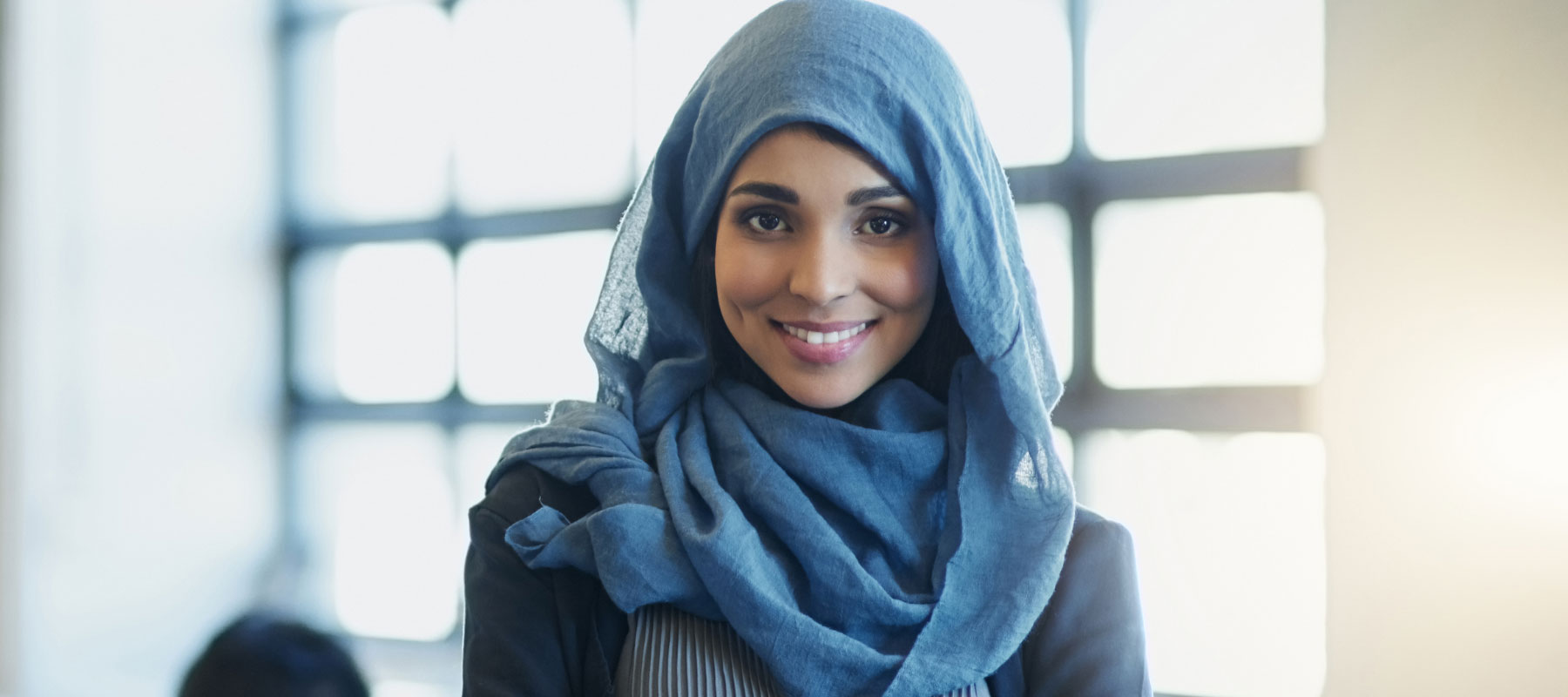 Woman in a head scarf smiles at the camera.