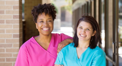 Two women smile.