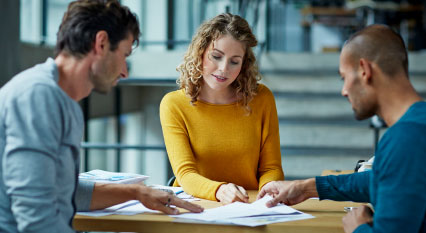 Two men and one woman looking at papers