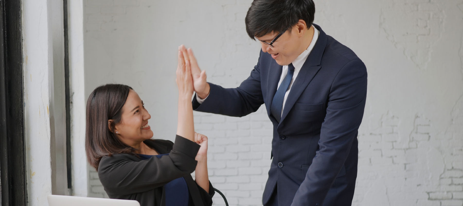 Corporate man and woman giving eachother a high five