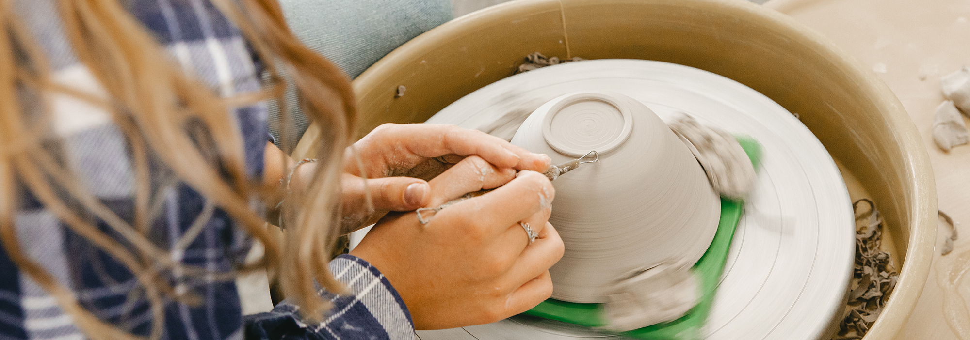 A Normandale student throws pottery on a yellow pottery wheel. 