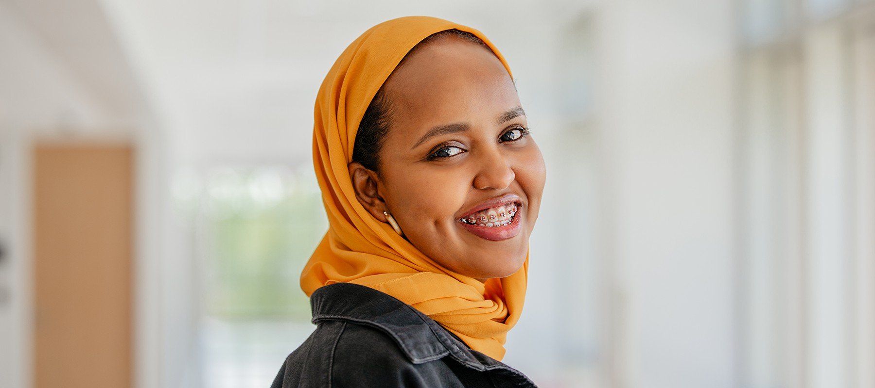 A Normandale Student in a yellow hijab smiles 