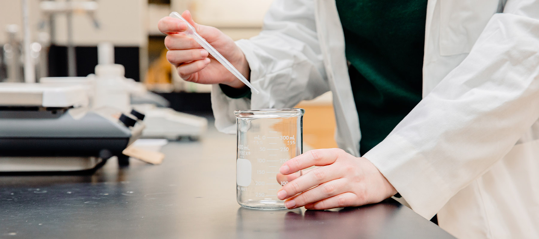 A Normandale chemistry student works with a beaker.