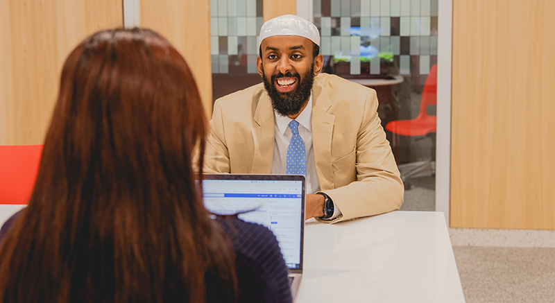 An advisor smiles at a student. 