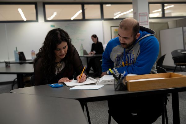 A student and a peer writing tutor work together.