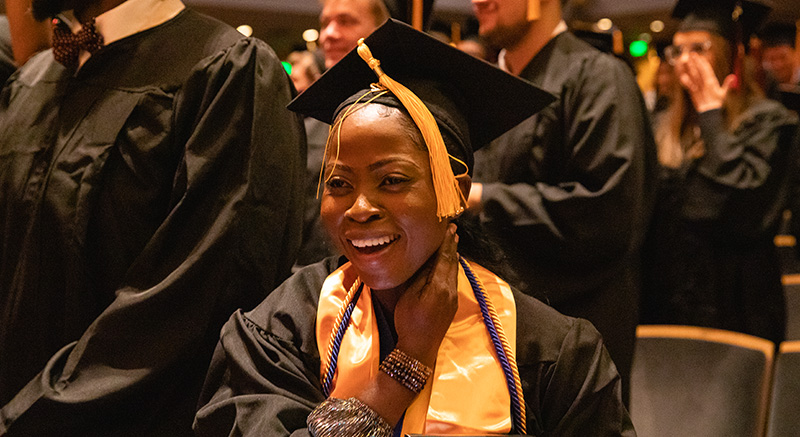 A student smiles in her cap and gown.