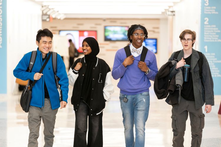 Four happy Normandale students walking the halls of Normandale
