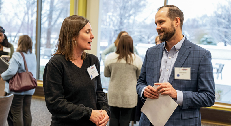 Two older people chat at a Normandale function.