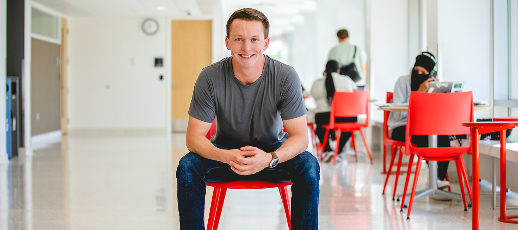 A Normandale student sits in a chair and smiles.