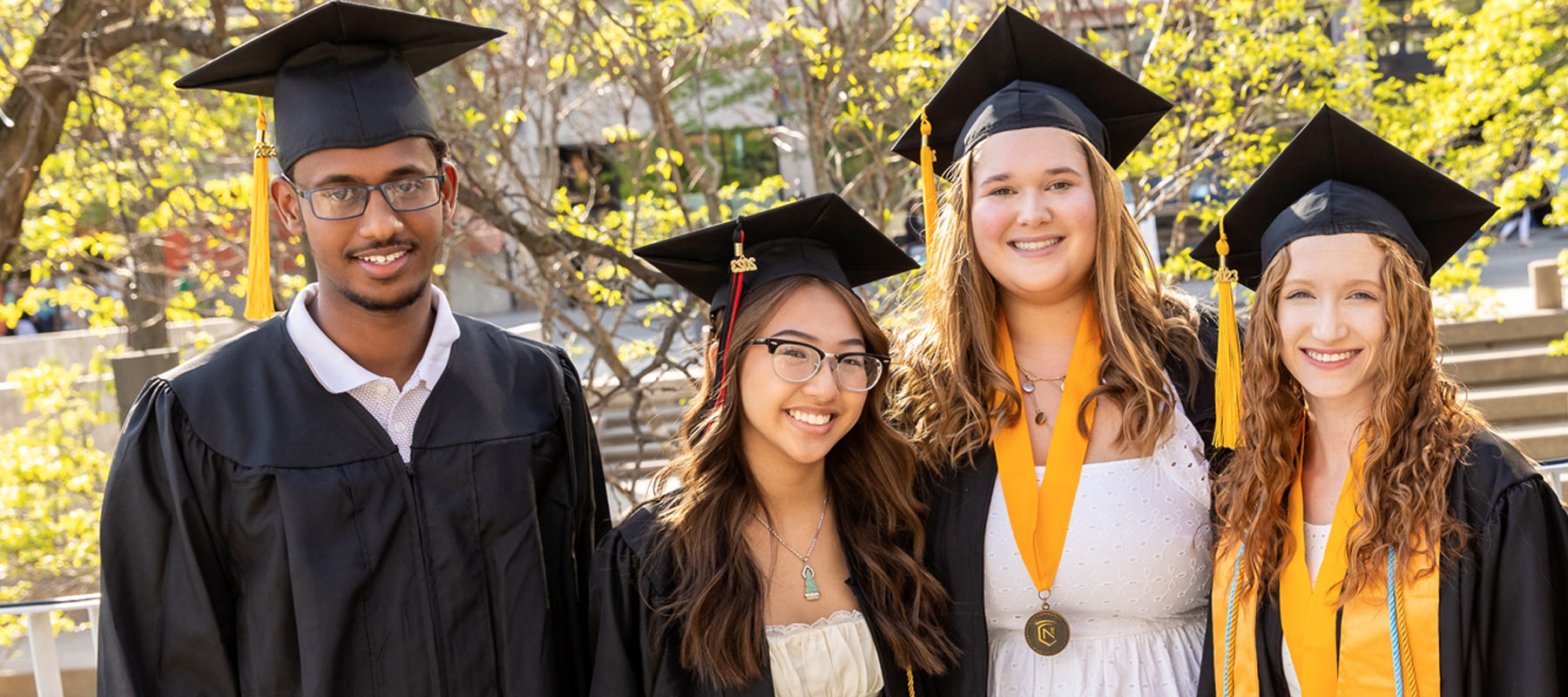 Normandale students smiling in graduation caps and gowns