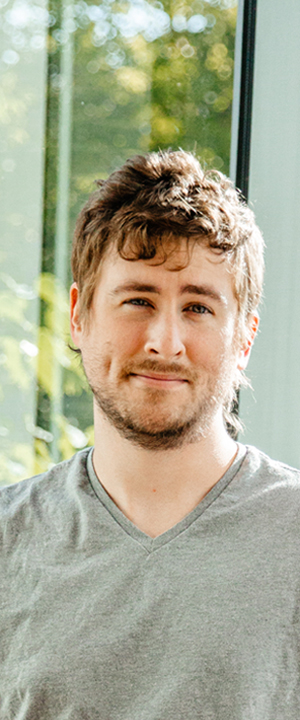 A Normandale student in front of a green background smiles at the camera.