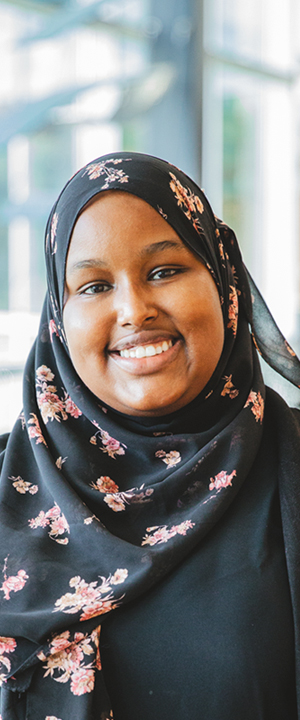 A Normandale student in a black head scarf smiles.