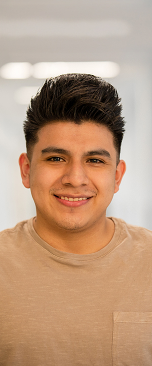 A Normandale student in a tan t-shirt smiles.