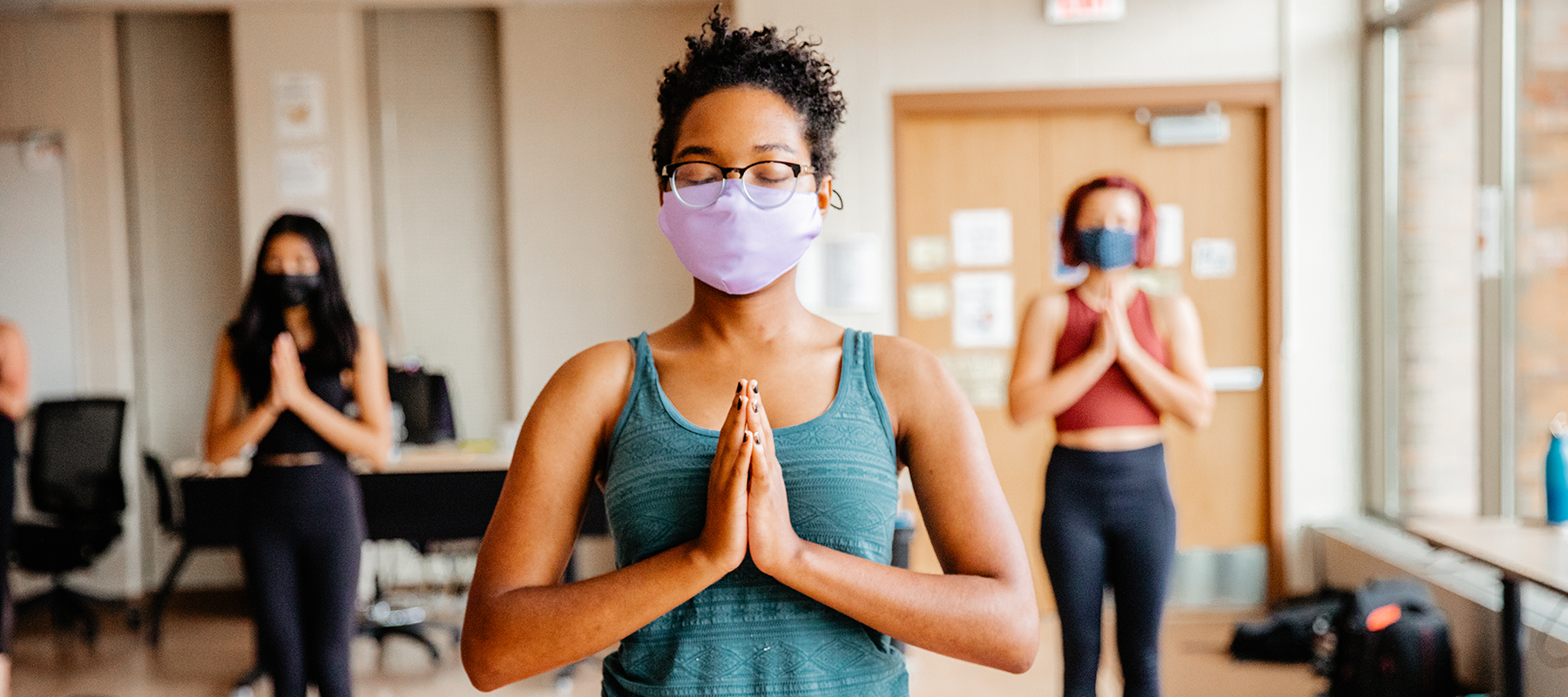 A Normandale student in a mask practices yoga.