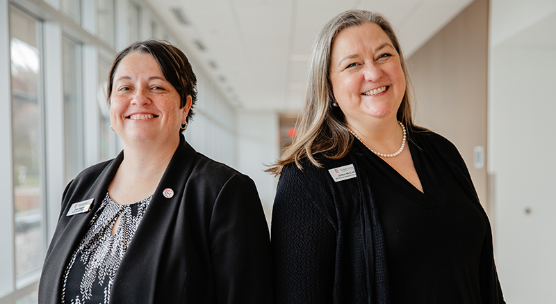 Two Normandale staff members smile at the camera.