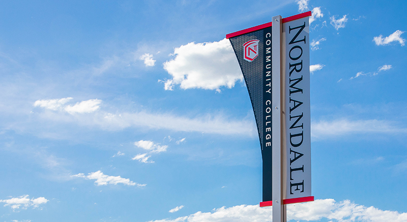 Normandale Community College flags fly on a flagpole.